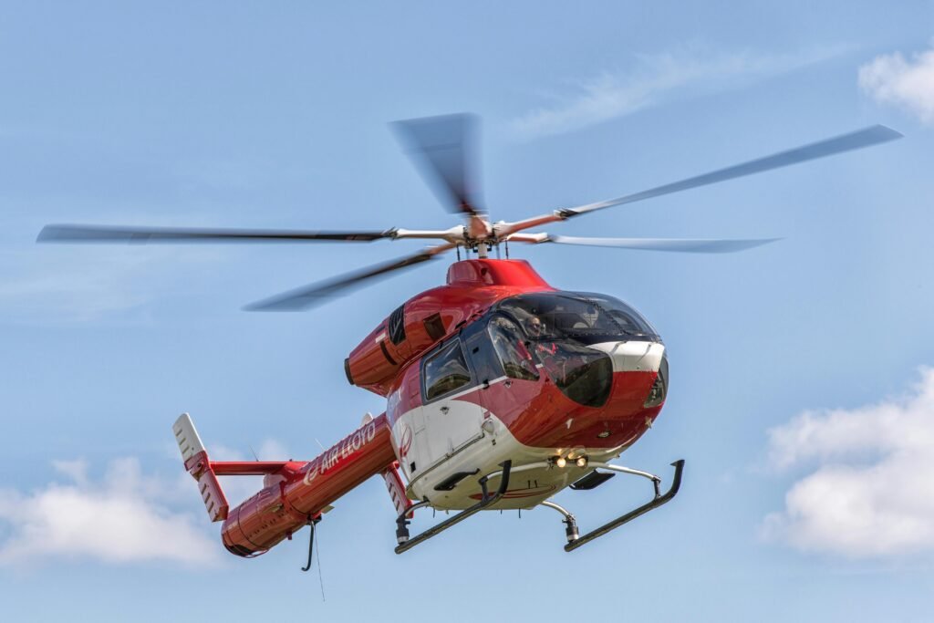 pexels-photo-18199318-18199318 A red helicopter from Air Lloyd flying against a clear blue sky in Hamburg, Germany.
